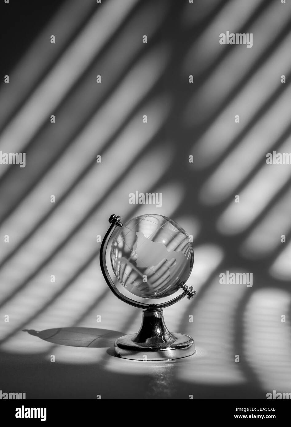 Kleine Erdkugel aus Kristallglas auf gestreiftem grauem Schatten, Licht und Schatten, vertikalem Hintergrund. Globales Unternehmensnetzwerk, digitale Technologie, EAR Stockfoto