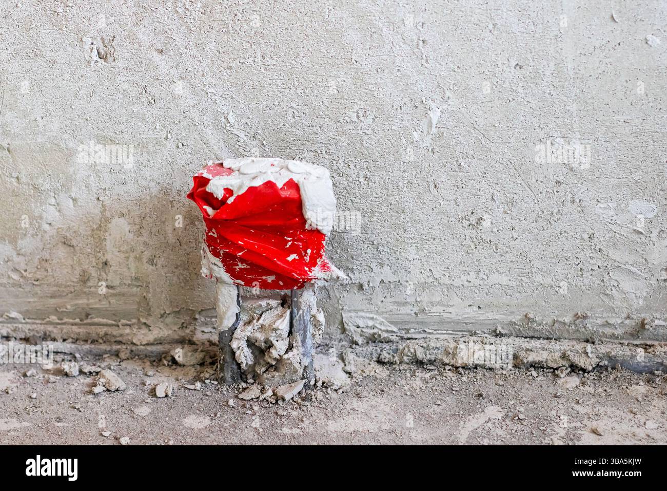 Eine kalte Dose Limonade wird direkt neben einer stabilen Wand auf den Boden gestellt, wodurch ein interessanter Kontrast zwischen den beiden Oberflächen entsteht Stockfoto