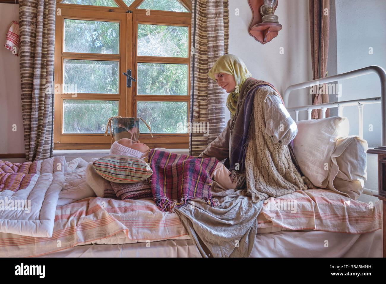 Eine Mutter sitzt mit ihrem verletzten Baby auf einem Bett, Kind in einer Krankenstation. Im Canakkale Hospital Museum in Gallipoli, Türkei. Stockfoto