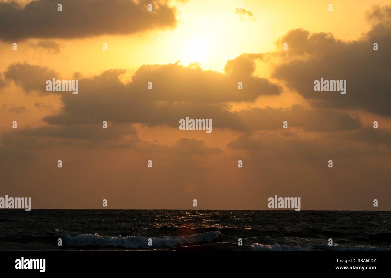 Goldener Sonnenuntergangshimmel mit dramatischen dunklen Wolken und Sonnenstrahlen, die durch eine atemberaubende Naturszene strömen. Stockfoto