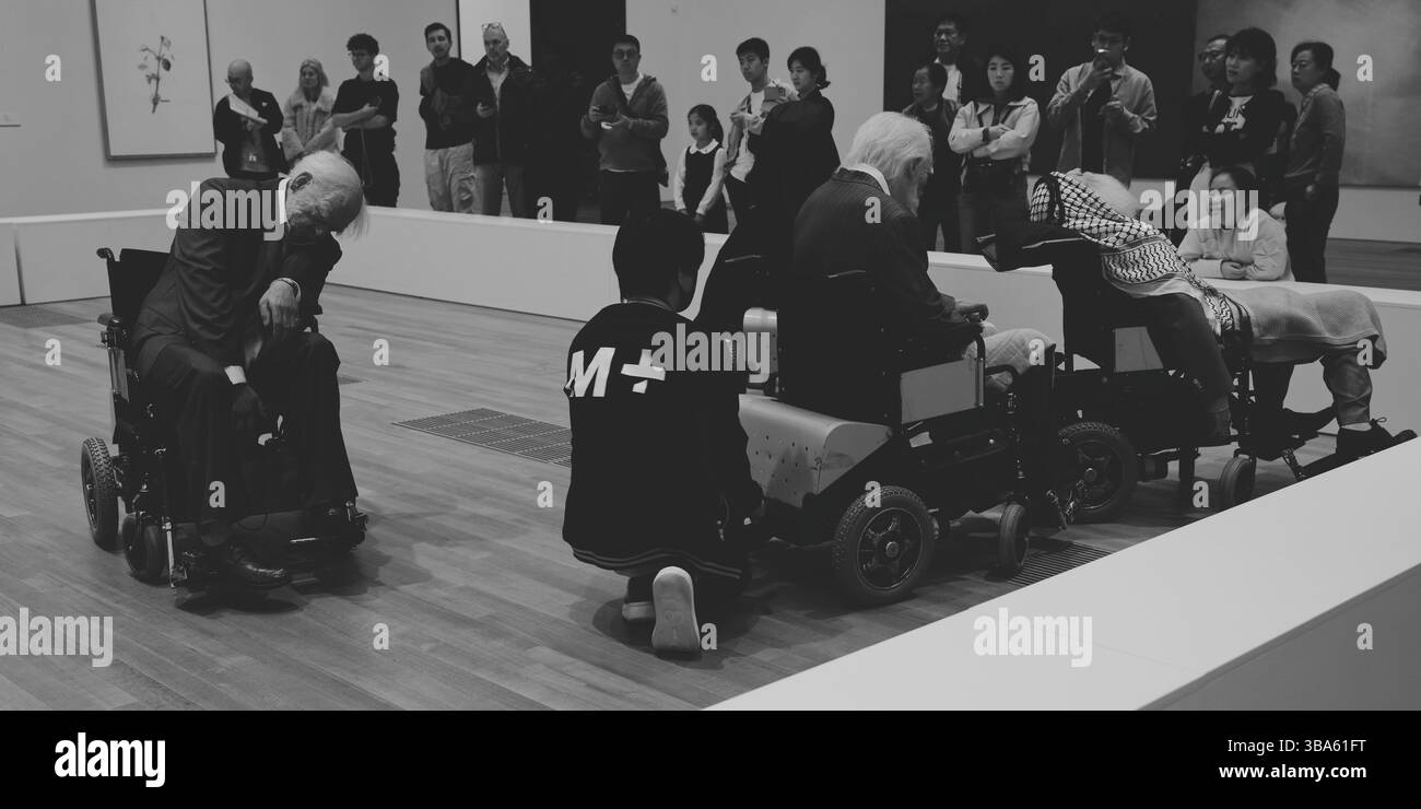 Museumsbesucher beobachten die verstörende Installation „Old Persons Home“, ein Mitarbeiter passt eine der hyperrealistischen Figuren an Stockfoto