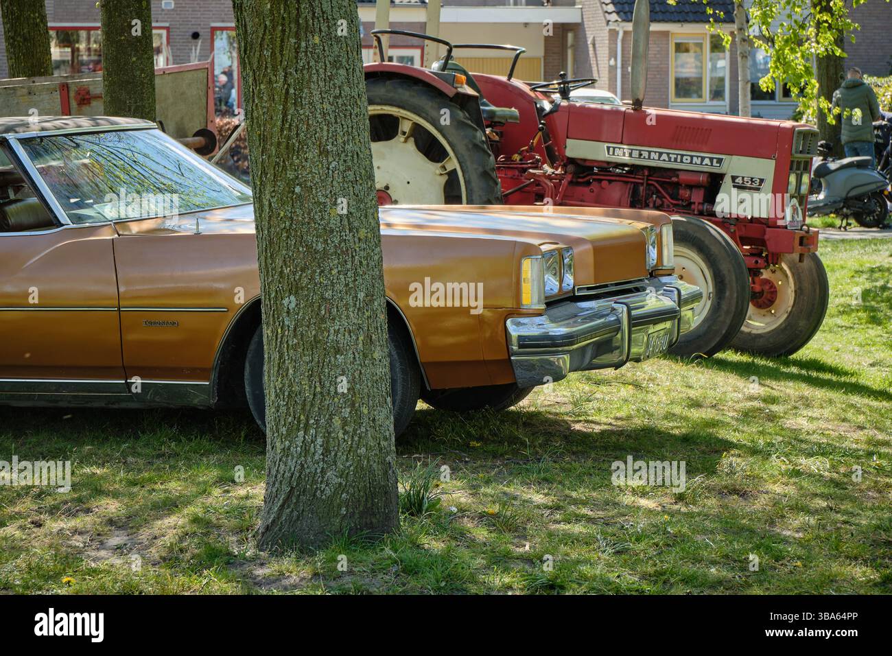 20. April 2025 - Limmen-Niederlande: Ein amerikanischer Oldtimer und ein Traktor der International 453 parkten unter Bäumen während des Bloemendagen Blumenevents in L Stockfoto