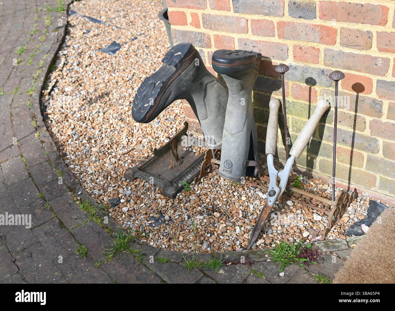 Gummistiefel und Vintage-Gartenschere im sonnigen Garten. Stockfoto