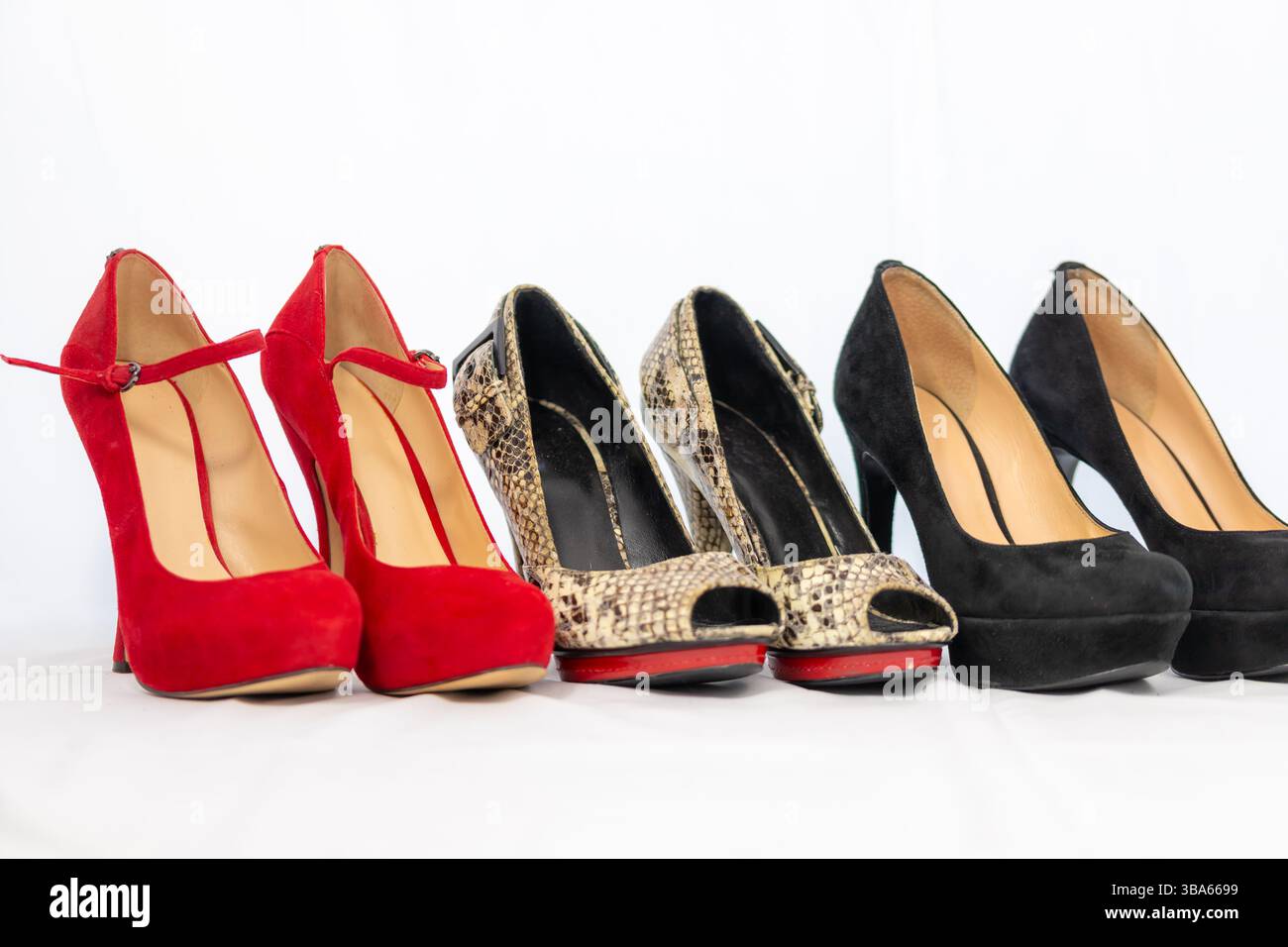 Drei Paar Damenpumpen mit hohen Hebeln in Reihe rot, schwarz und Schlange. Mit weißem Hintergrund. Hochwertige Fotos Stockfoto