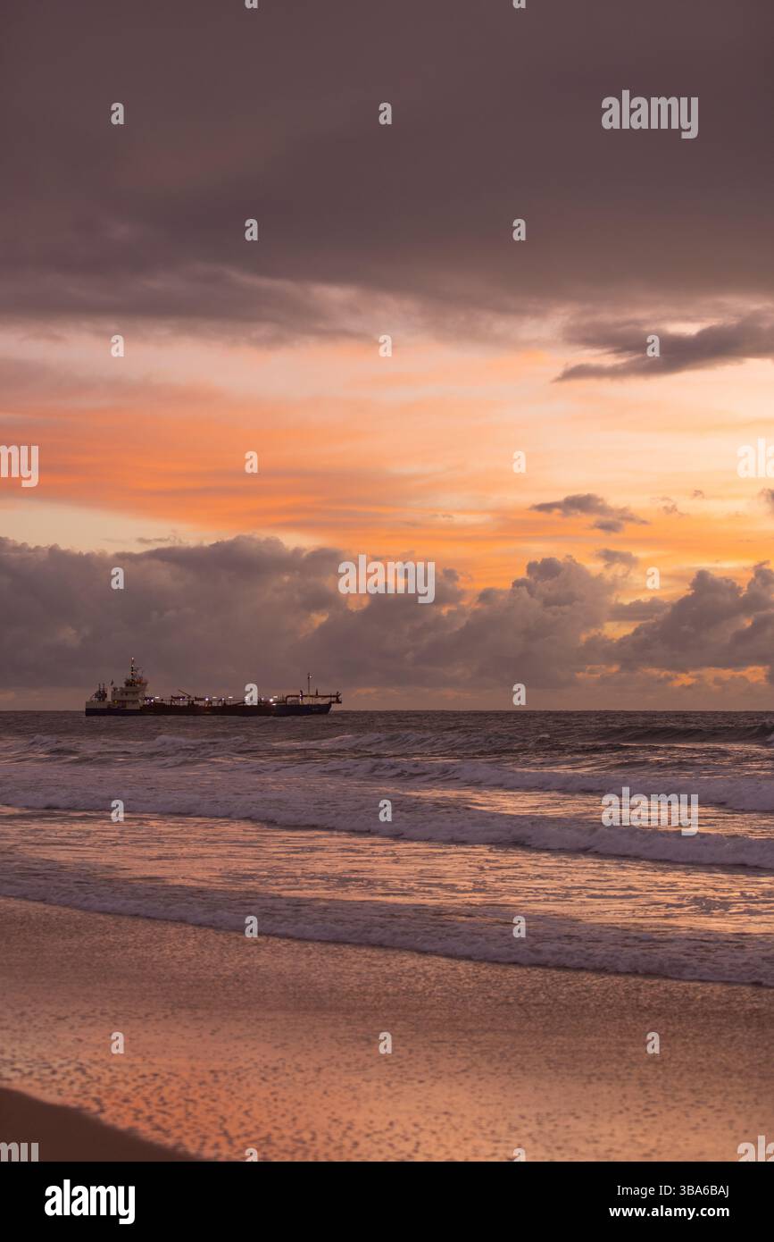Orange und Lila Sonnenaufgang taucht Schiff und Meer auf, um Zyklone zu erholen Stockfoto