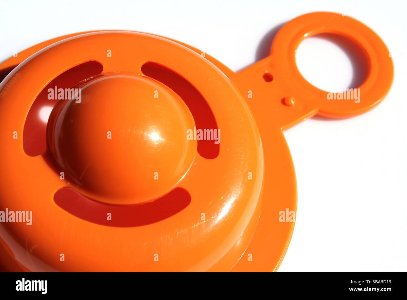 Nahaufnahme eines orangen Eiertrenners Küchenutensil vor weißem Hintergrund Stockfoto