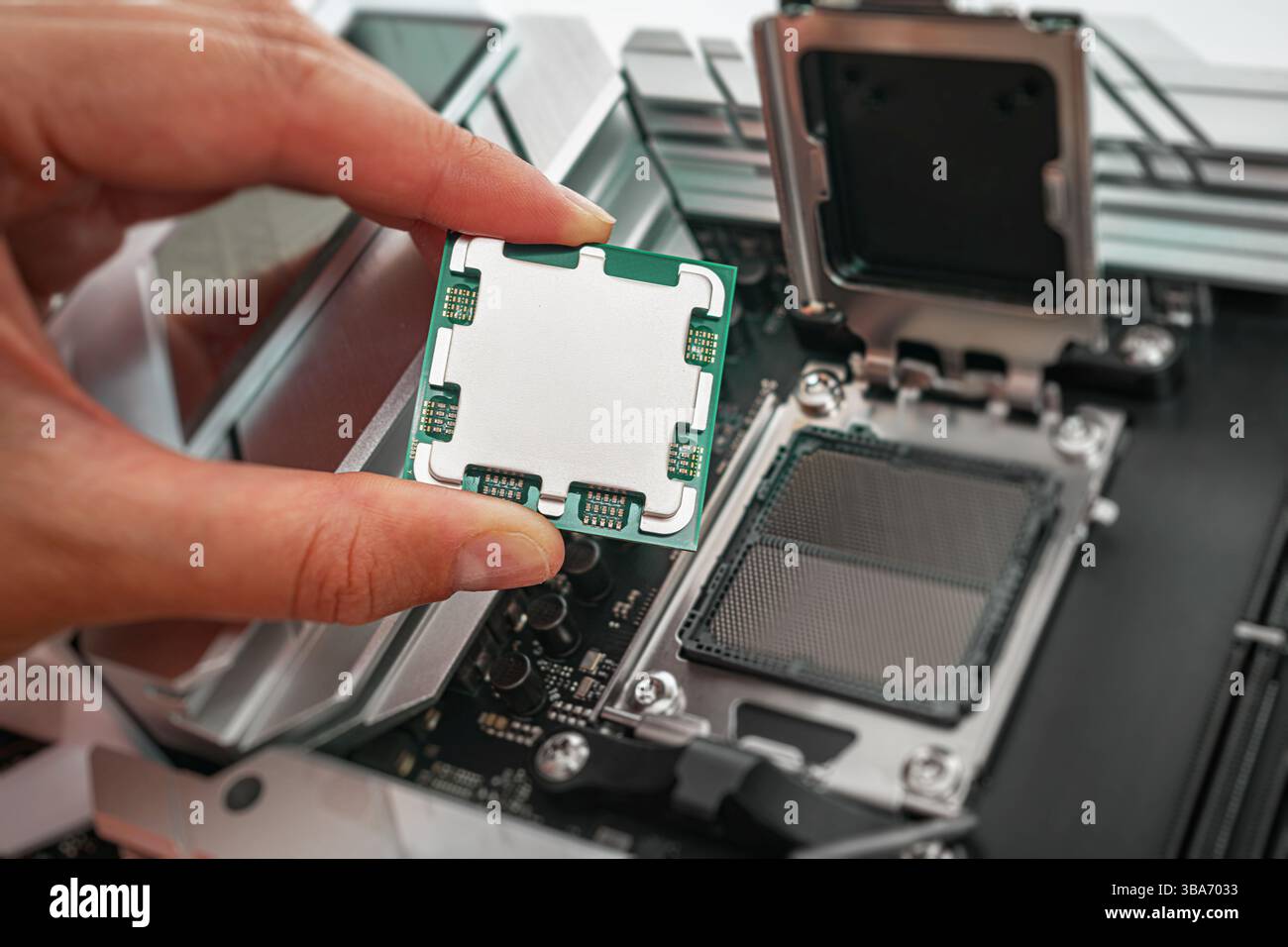 Eine Person hält einen Computerprozessor vorsichtig über einen Sockel auf der Hauptplatine Stockfoto