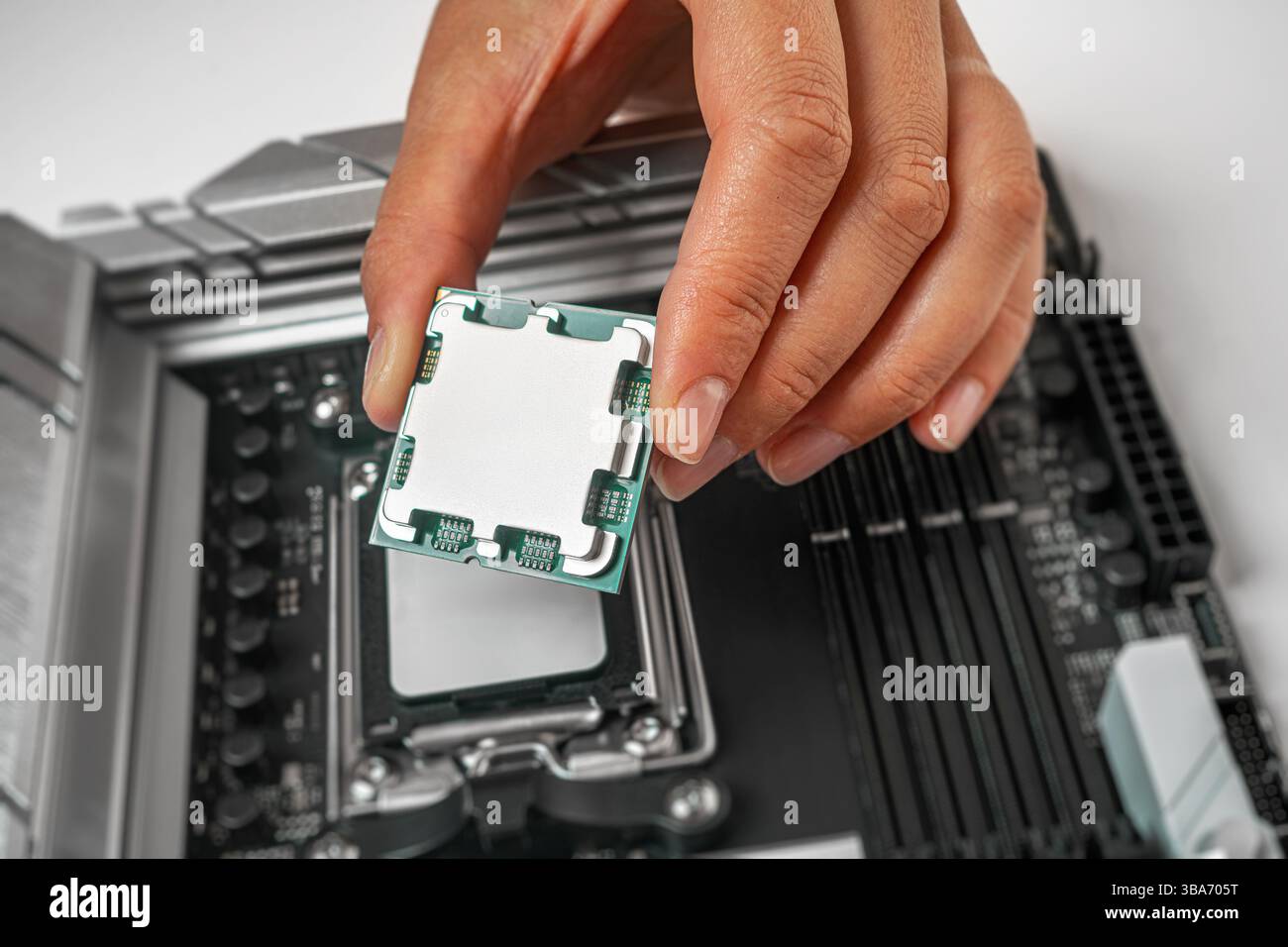 Eine Person hält einen Computerprozessor vorsichtig über einen Sockel auf der Hauptplatine Stockfoto