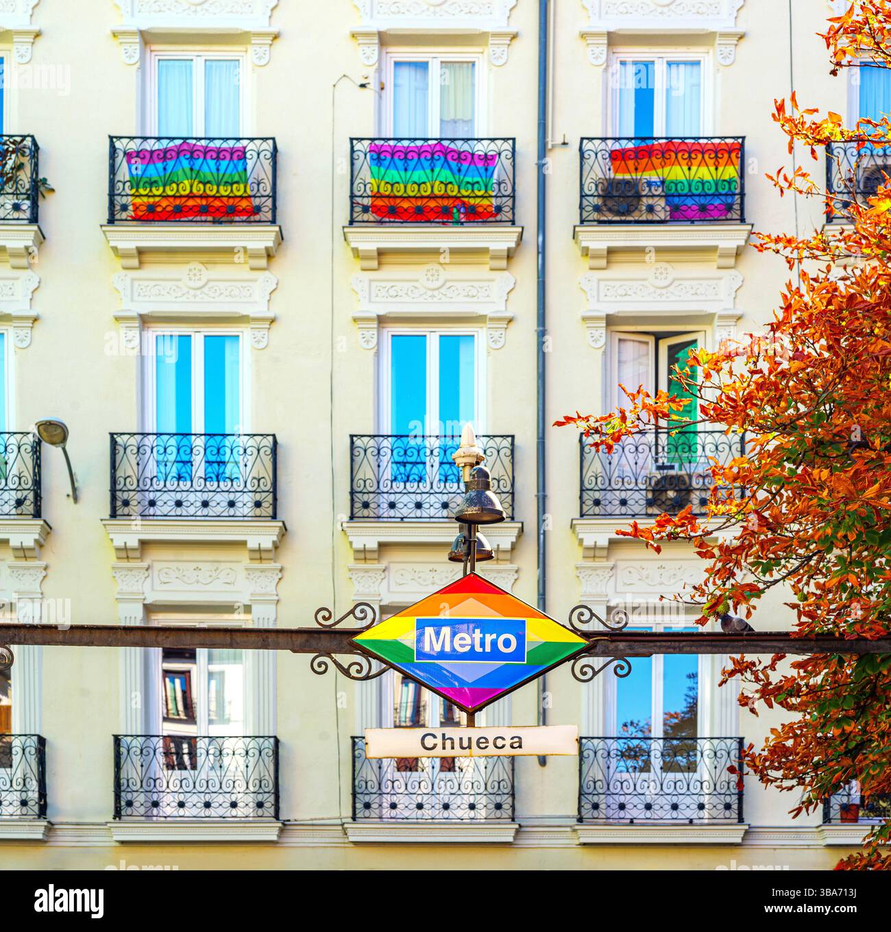 Chueca Metro-Schild in Regenbogenfarben und Balkons mit Pride-Flaggen für die Feier des Gay Pride Day. Stockfoto