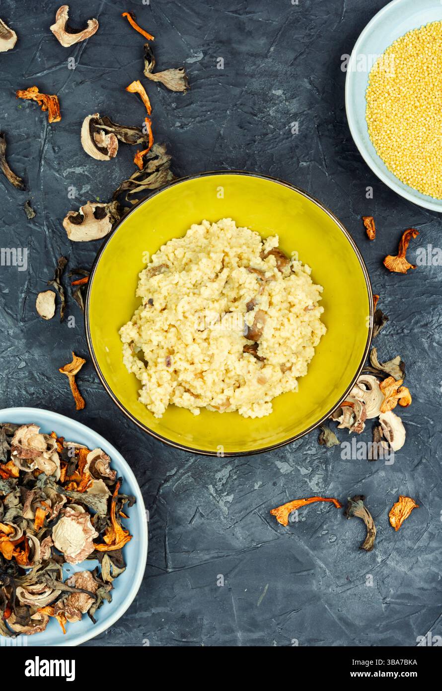 Hirsebrei mit Waldpilzen in einer Schüssel auf einem Betonküchentisch. Stockfoto