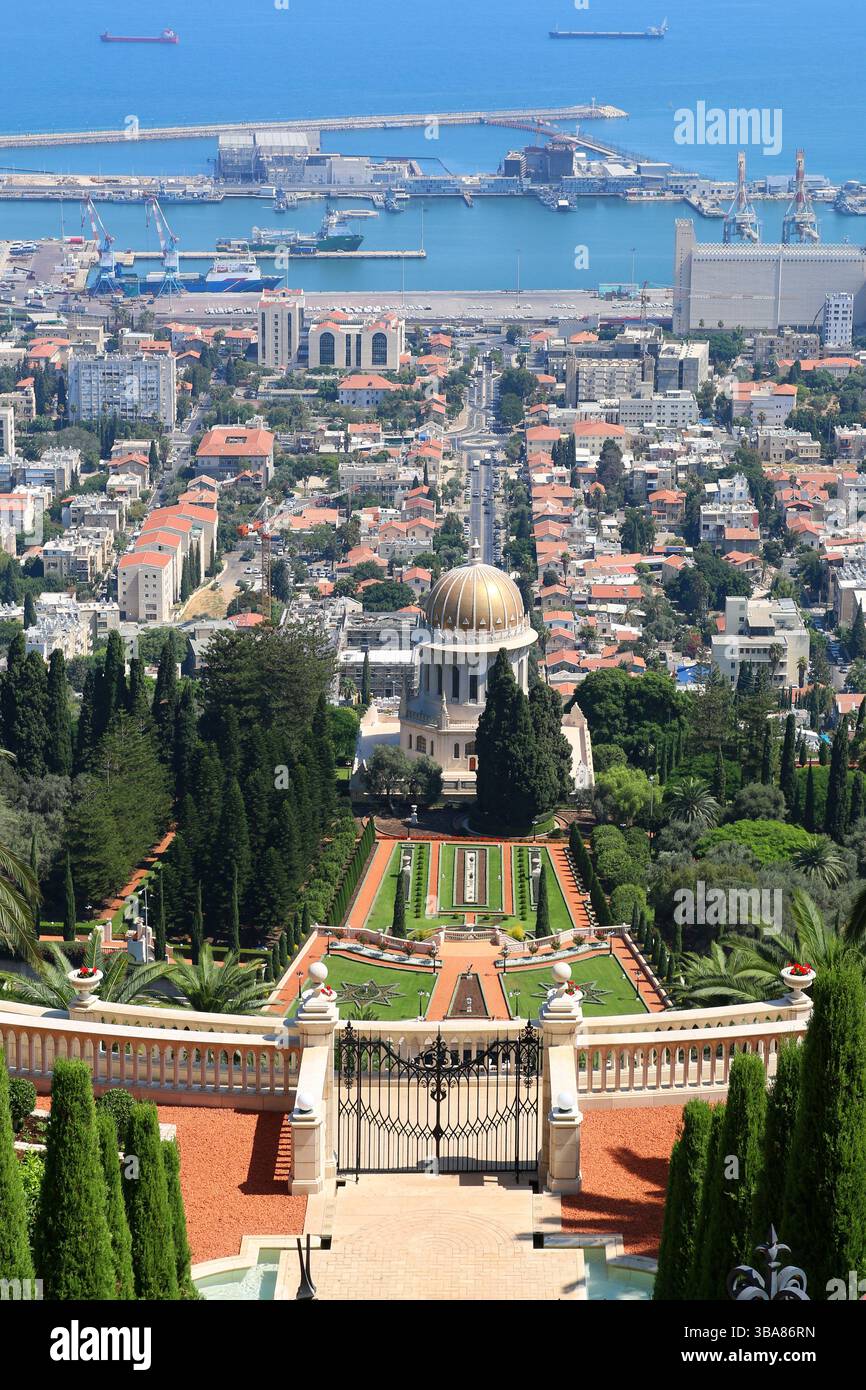 Blick auf die Bahá’í-Gärten und den Schrein der Báb in Haifa, Israel, mit symmetrischen Terrassen und Haifa-Hafen und Mittelmeer im Hintergrund. Stockfoto