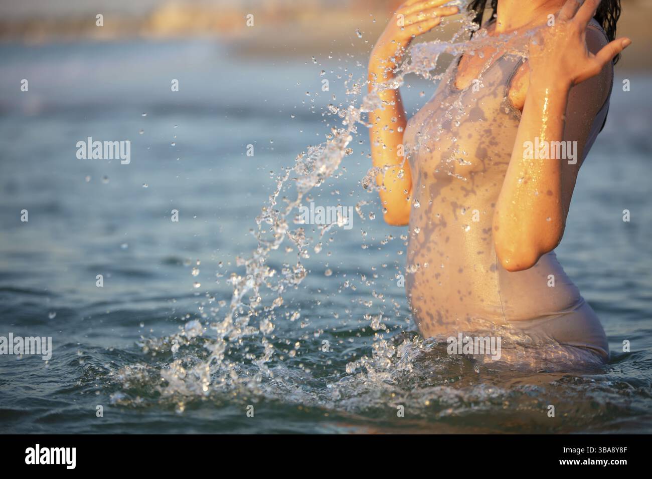 Eine Frau in einem T-Shirt sprüht Meerwasser. Schwimmen im Meer Stockfoto