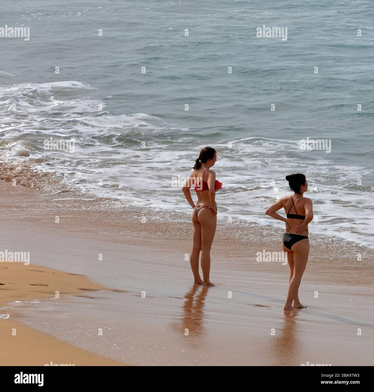 Zwei Frauen in Bikinis stehen an der Küste, Fuerteventura, Kanarischen Inseln, Spanien. Vom November 2024 Stockfoto