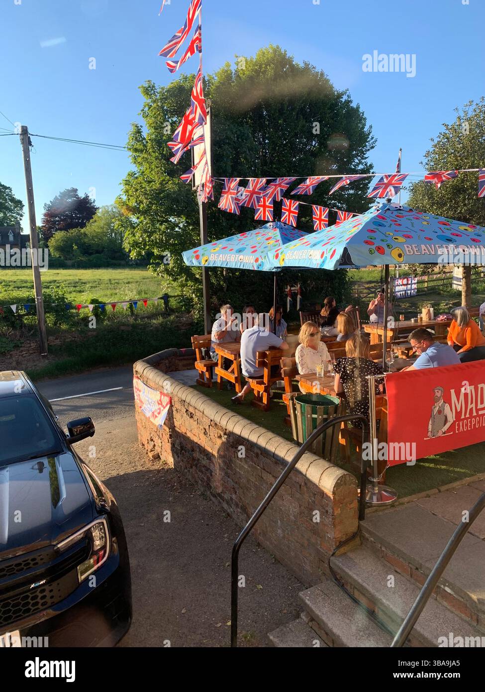 Menschen essen in einer Kneipe essen Essen Soldaten Militärplakat Kriegsflagge 80 Jahre Tag Veranstaltung Flaggen feiern das Ende des Krieges - Smartphone-aufgenommenes Stockfoto