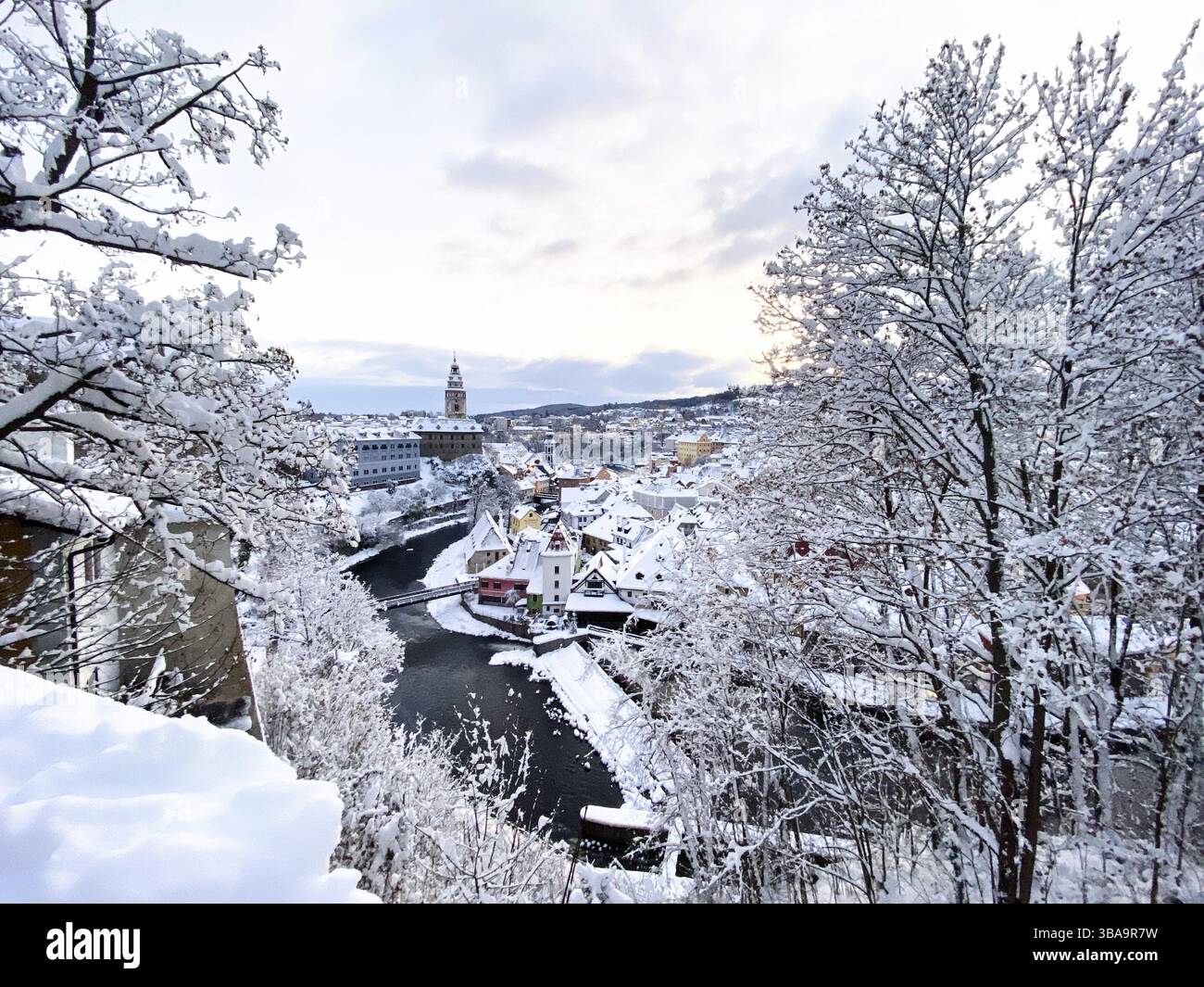 cesky Krumlov, UNESCO. Historische Stadt mit Schloss und Kirche bei Sonnenaufgang. Wunderschöne Winterlandschaft am Morgen mit einem beleuchteten Denkmal. Schneebedeckter Zick Stockfoto