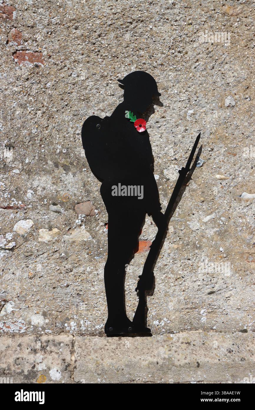 Soldatensilhouette mit Mohn gegen Steinmauer der Kirche, Great Easton (ein Dorf und eine Zivilpfarrei im Bezirk Uttlesford), Essex, England Stockfoto