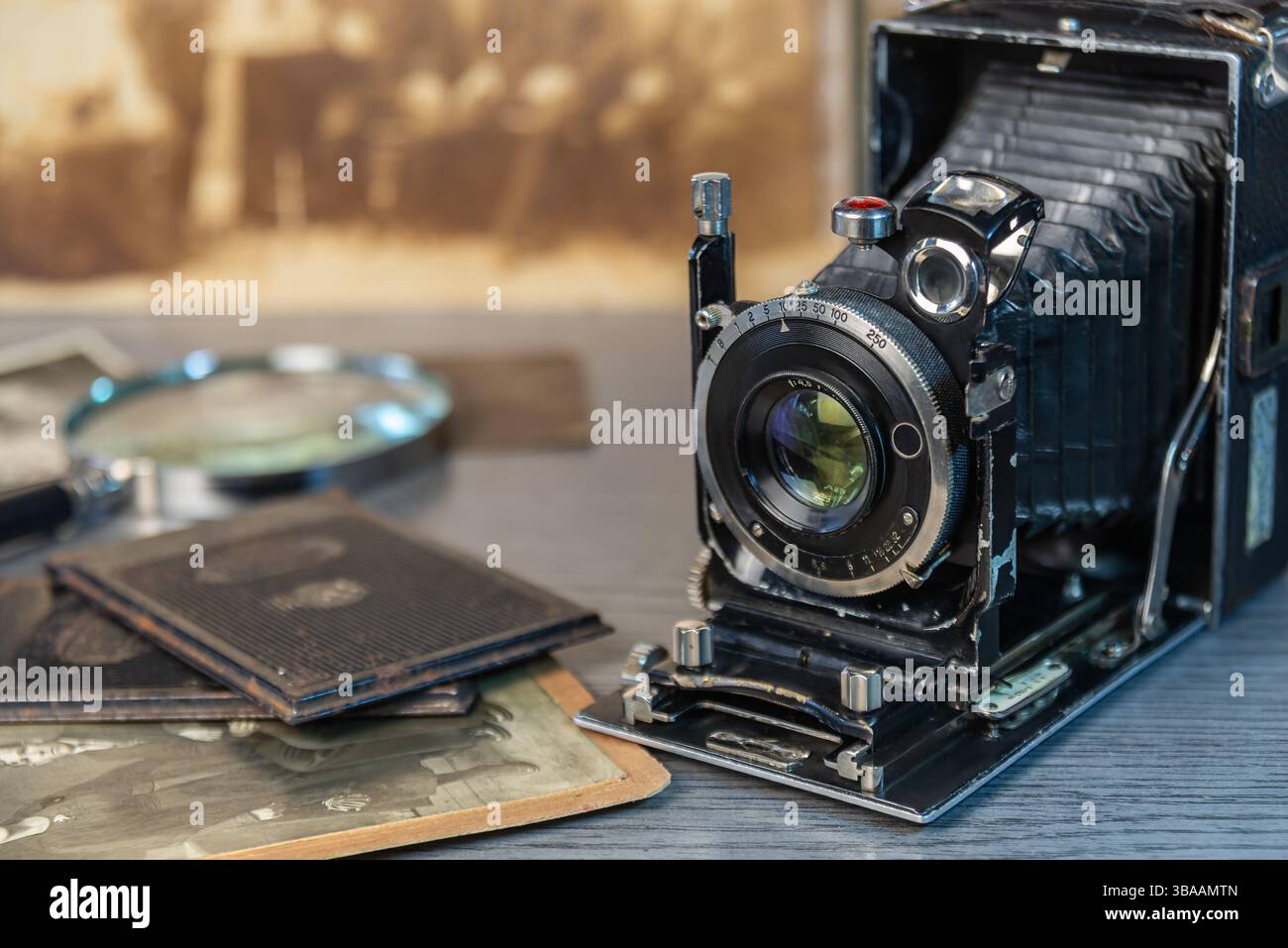 Eine alte Kamera sitzt auf einer Holzoberfläche, umgeben von alten Fotos, die Erinnerungen an vergangene Momente und Geschichten wecken. Stockfoto