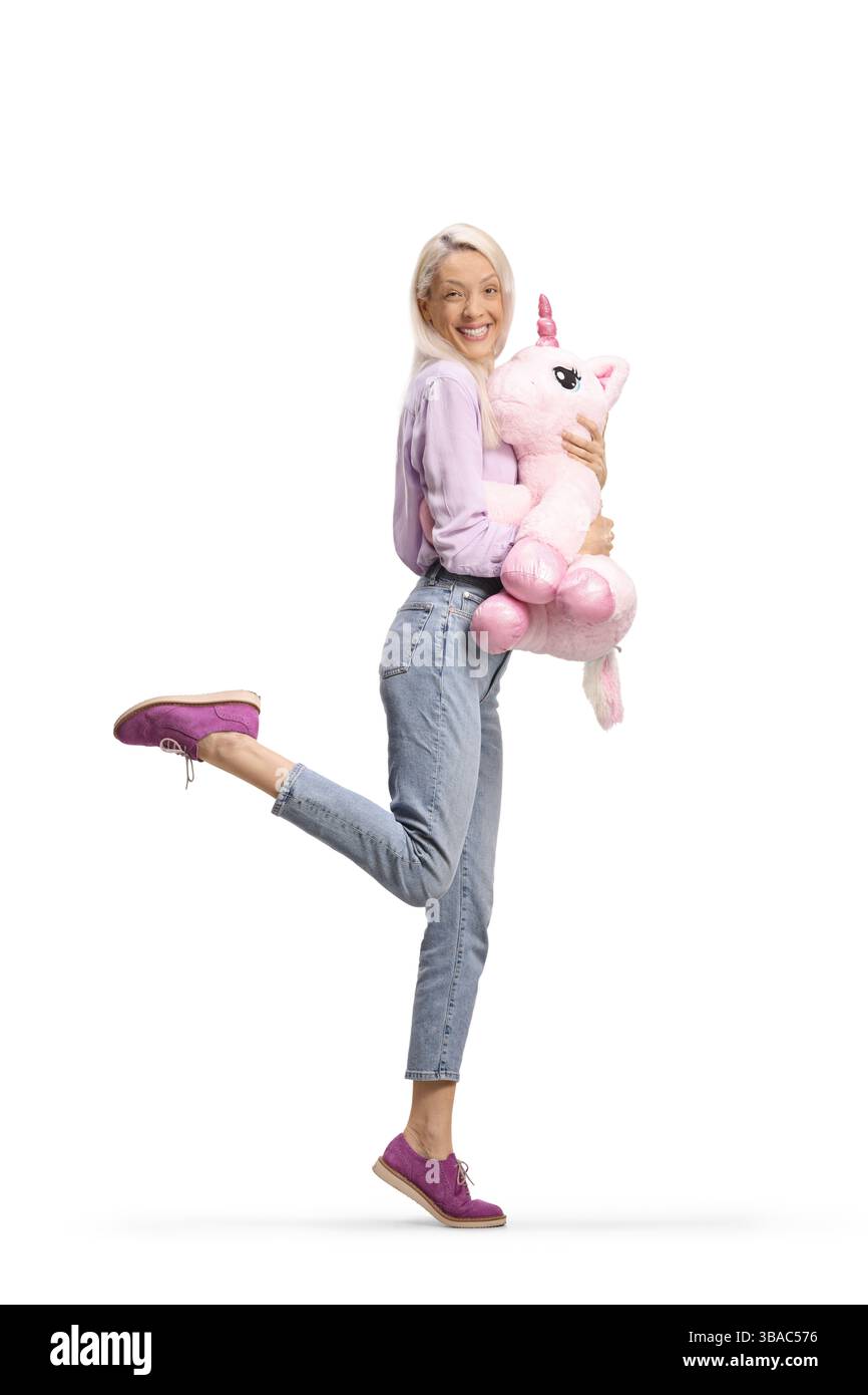 Glückliche Frau, die ein großes Einhornspielzeug auf weißem Hintergrund hält Stockfoto
