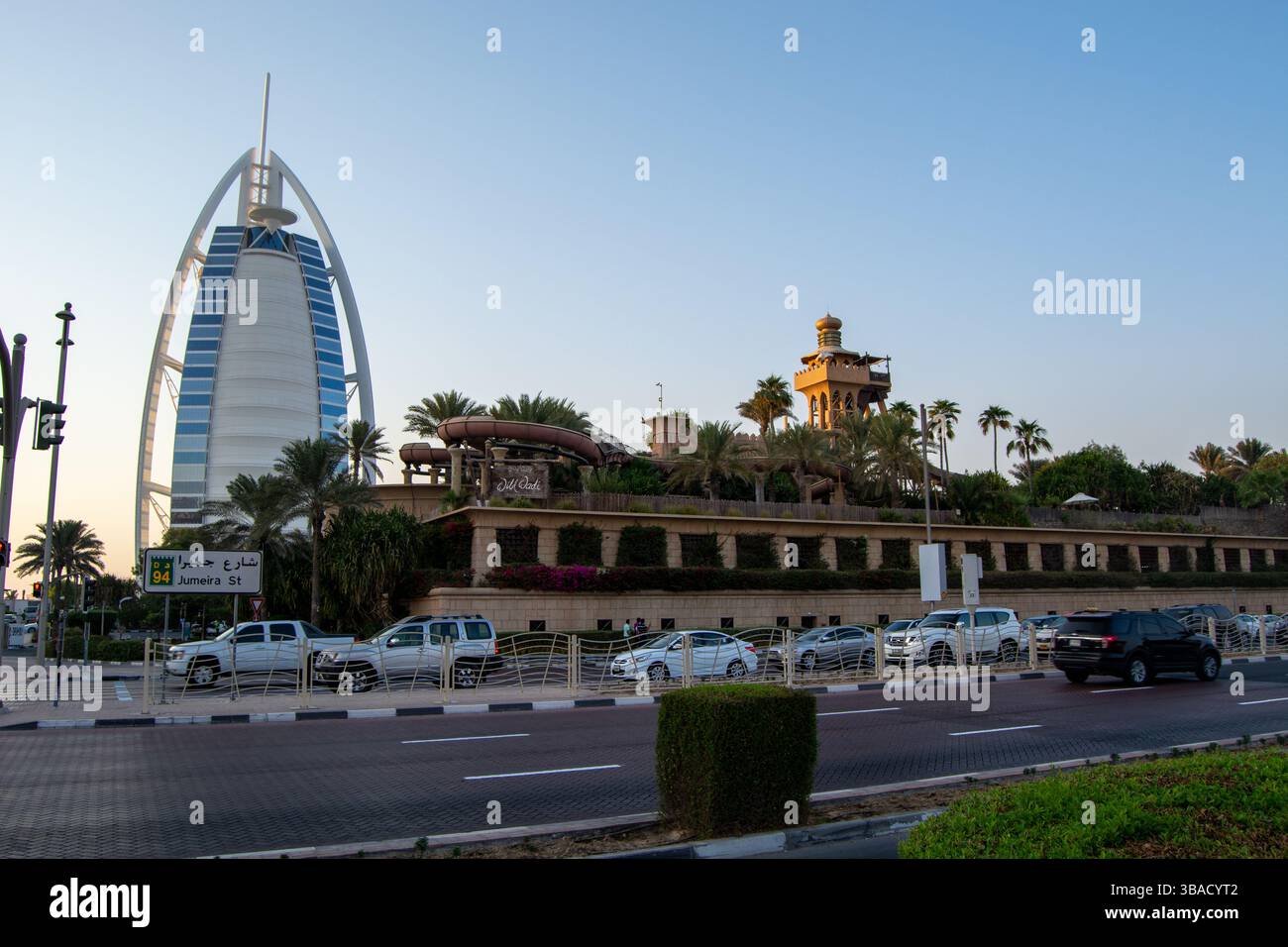 Blick auf das Burj Al Arab Hotel in Dubai, mit seiner ikonischen segelähnlichen Struktur und einem Landschaftsbereich mit Palmen und einem traditionellen bui Stockfoto
