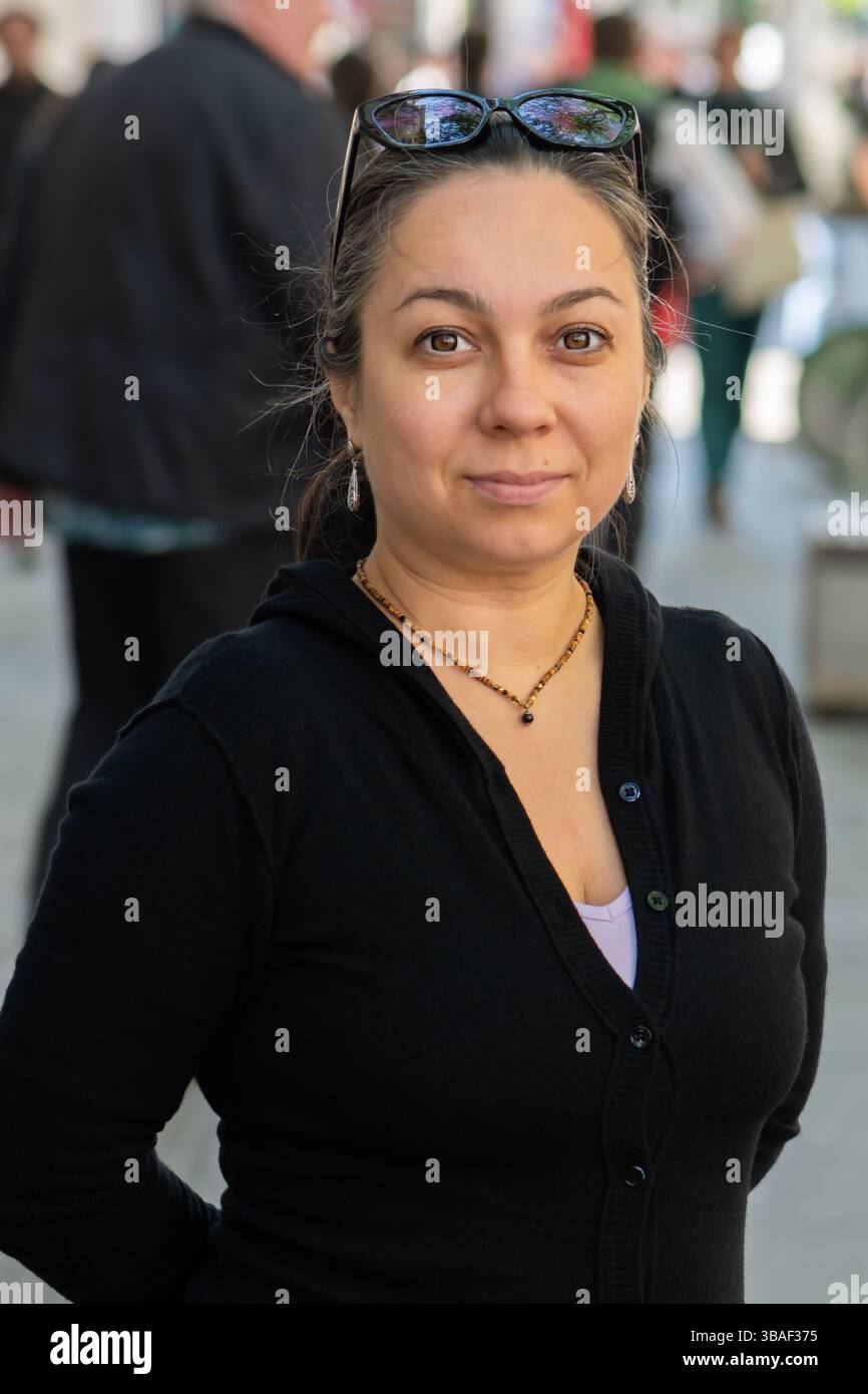 Straßenszene mit einer 40-45-jährigen Frau, die direkt in die Kamera schaut Stockfoto