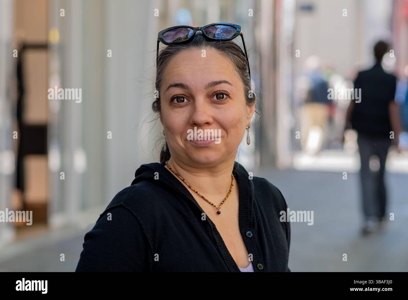 Eine 40-45-jährige Frau in schwarzer Kleidung posiert tagsüber auf einer Straße Stockfoto