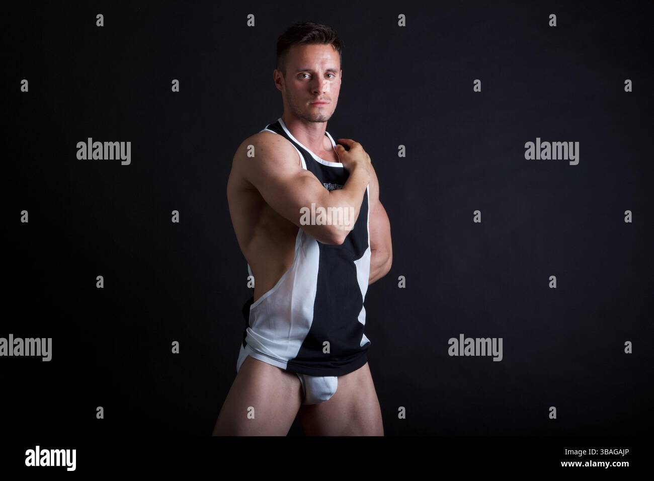 Männliches Modell mit einem Arm über der Brust und der Hand auf der Schulter Stockfoto