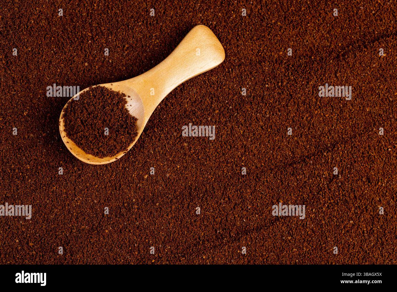 Gemahlener Kaffee und ein kleiner Holzlöffel, eine große Anzahl gerösteter gemahlener Kaffeebohnen in Pulver und ein Holzlöffel, Nahaufnahme, Blick von oben Stockfoto