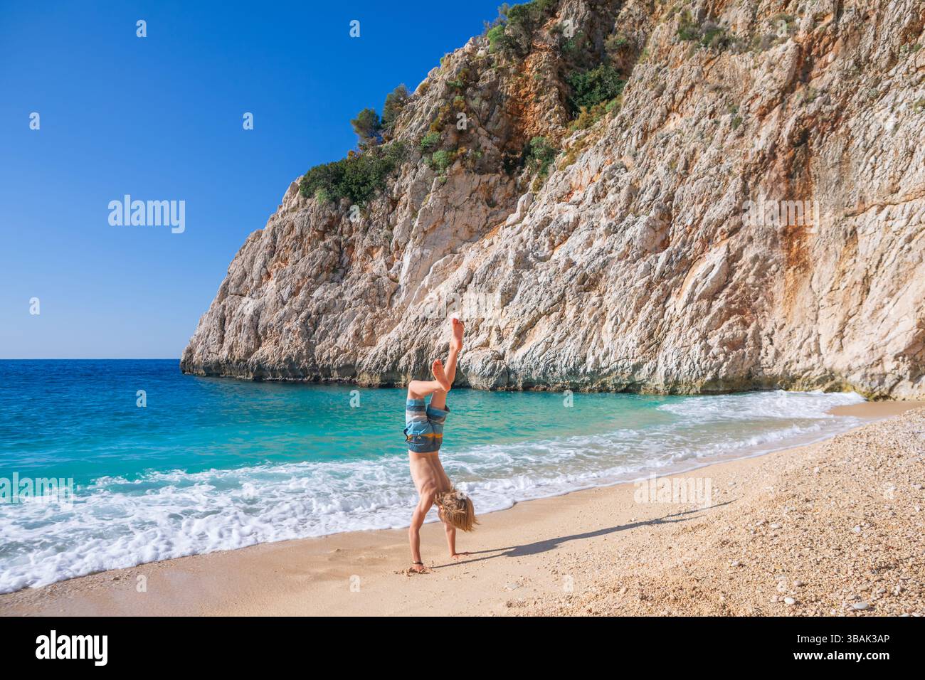 Glücklicher Junge, der Spaß am Kaputas Strand mit türkisfarbenem Meerwasser hat, Lycias Küste. Erholsamer Sommertag im Familienurlaub im Mittelmeer, Kas, Antalya Stockfoto