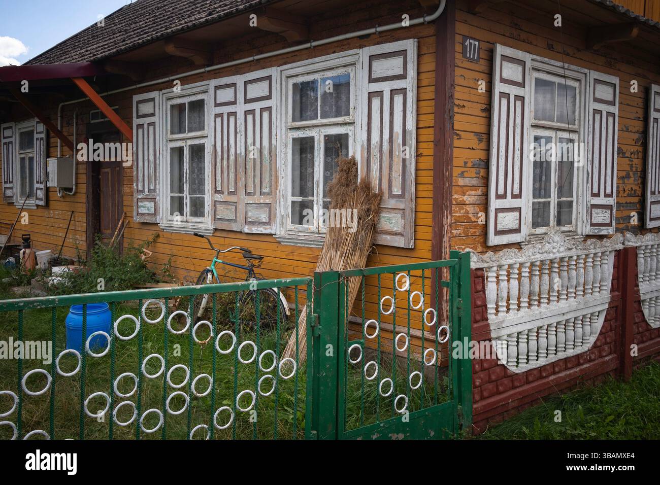 Ein Haus mit grünem Zaun und weißer Zierleiste. Der Zaun hat viele Kreise drauf Stockfoto