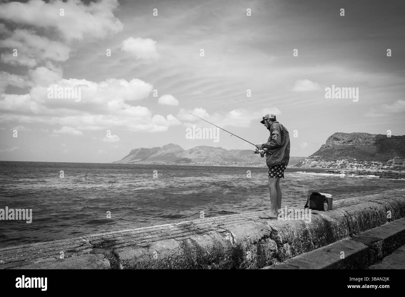 Fischer an der Mole des Kalk Bay Yachthafens, am Ufer der False Bay, östlich von Kapstadt Südafrika. Schwarzweißbild. Stockfoto