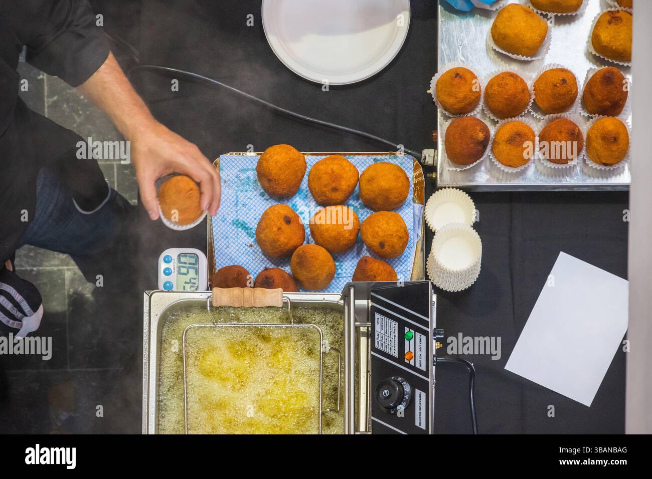 Blick von oben nach unten auf Arancini-Reisbällchen, die beim Sicily fest in Brick Lane, London, England zubereitet werden Stockfoto