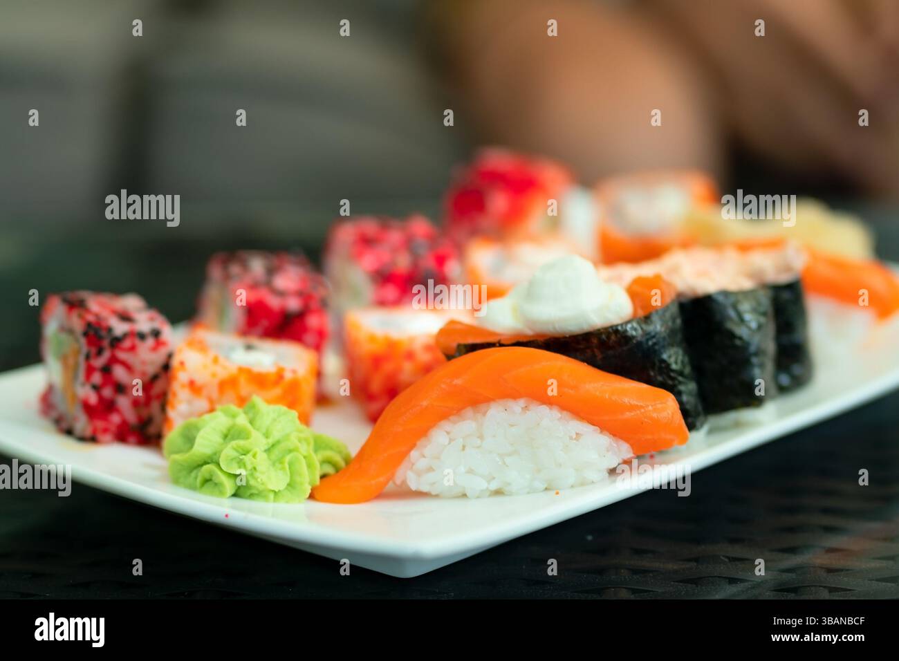 Kunstvoll arrangiertes japanisches Sushi und Brötchen mit Premium-Lachs. Gesunde Meeresfrüchte-Präsentation mit Wasabi und Ingwer. Stockfoto