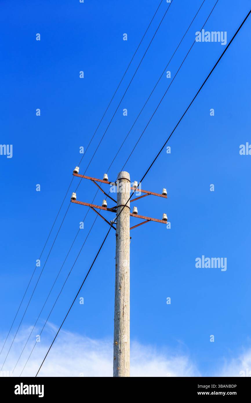 Telefonmast mit Drähten gegen einen blauen Himmel Stockfoto