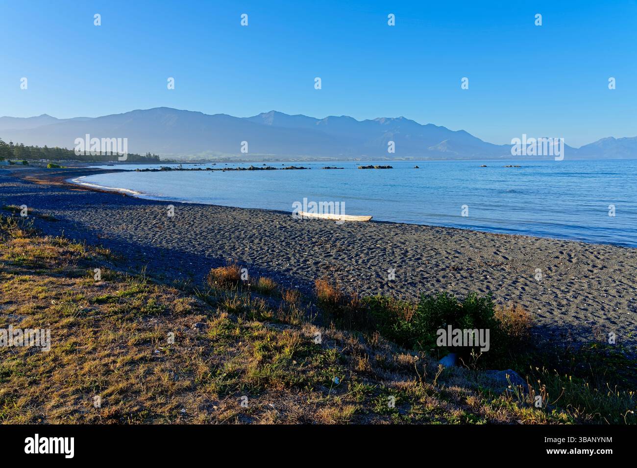 Blick entlang der weiten Weite des grauen Strandes Kaikoura an einem trüben Sommerabend. Stockfoto