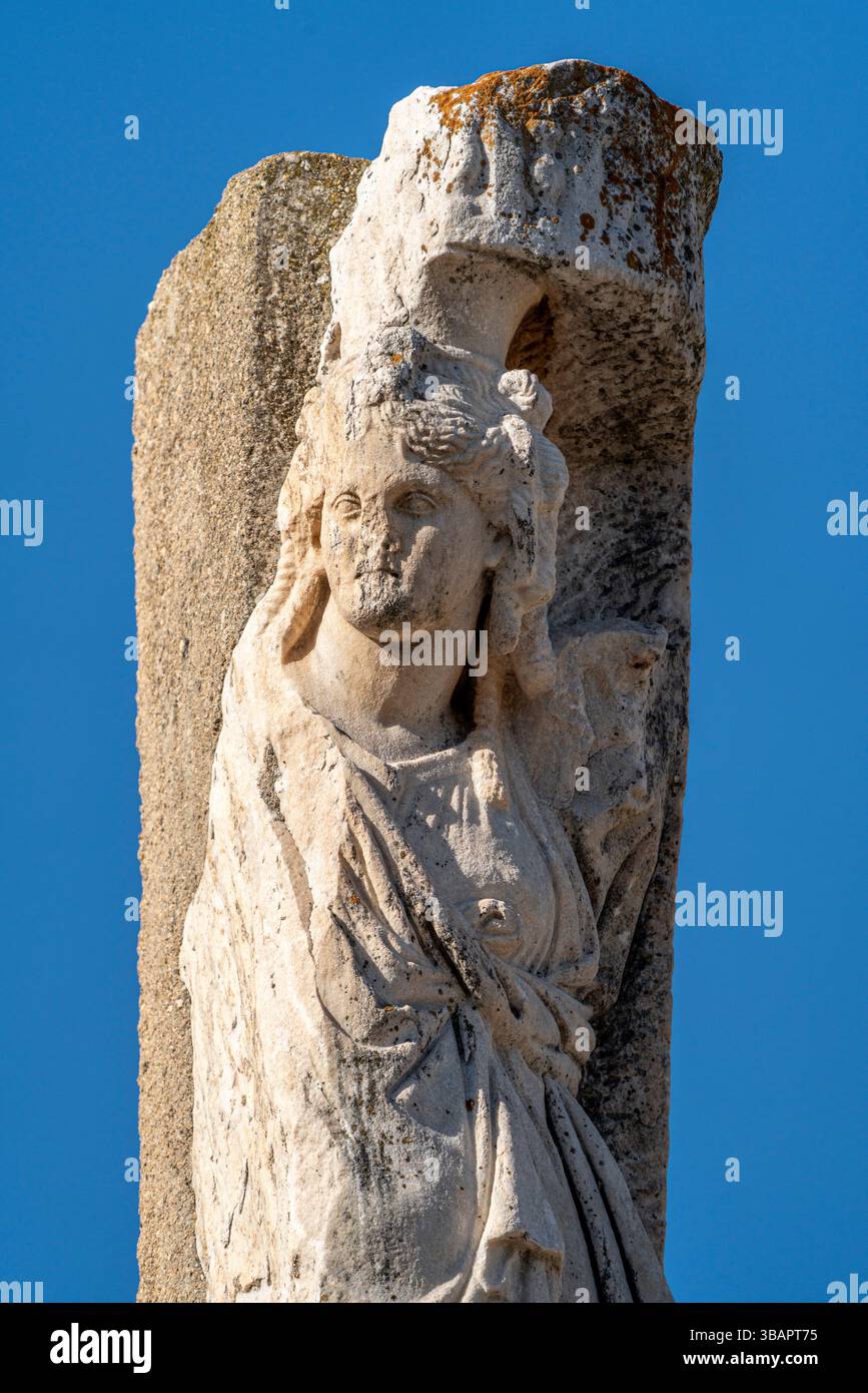 Statue aus dem Tempel des Domitians, ohne Kopf, in klassische Gewänder gehüllt, stehend gegen eine geschnitzte Steinsäule. Stockfoto