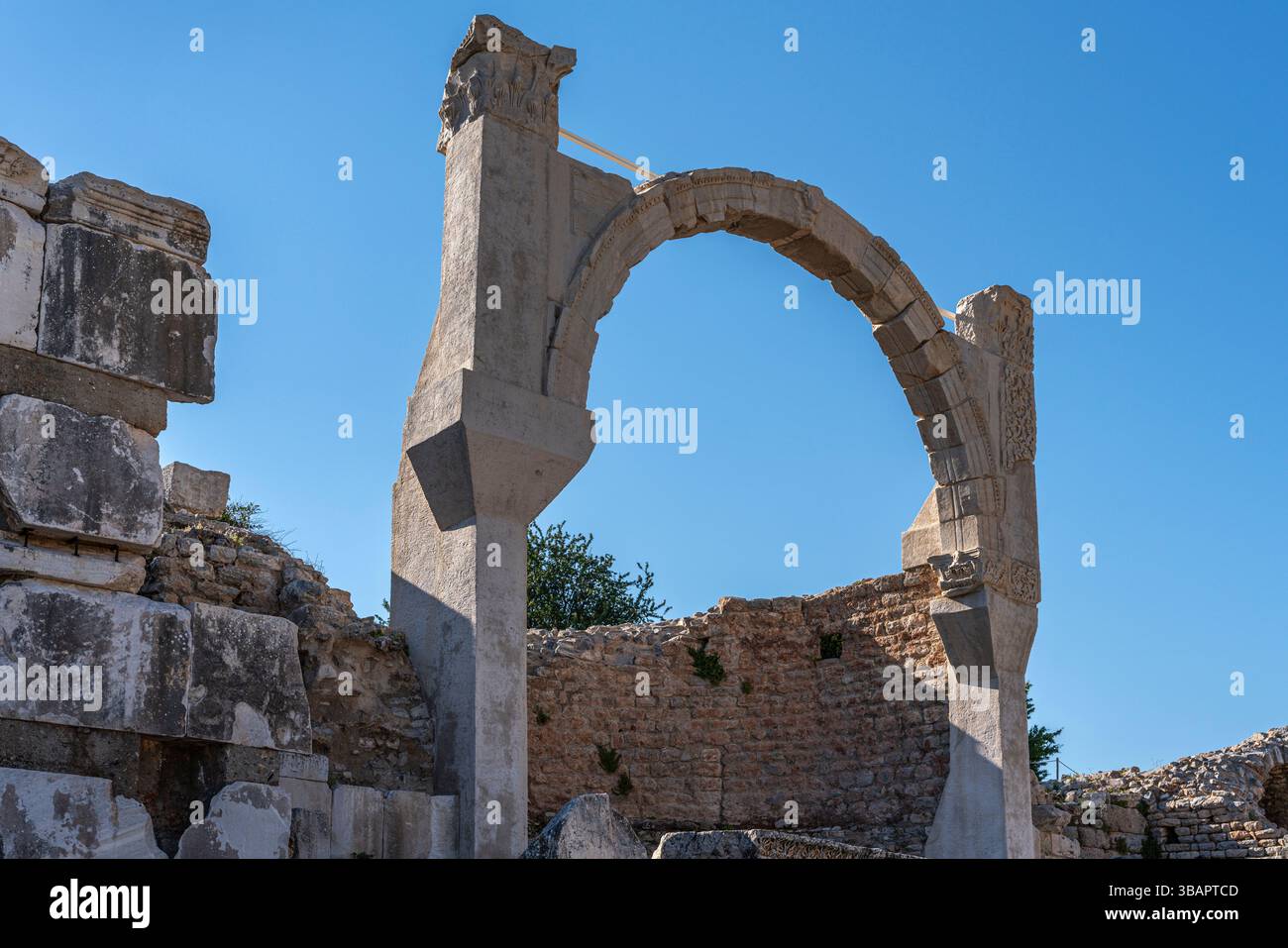 Tempel des Domitians in Ephesus mit gebrochenen Bogen- und Mauerfragmenten, die dem Kaiser gewidmet waren und einst über der Straße thronten. Stockfoto