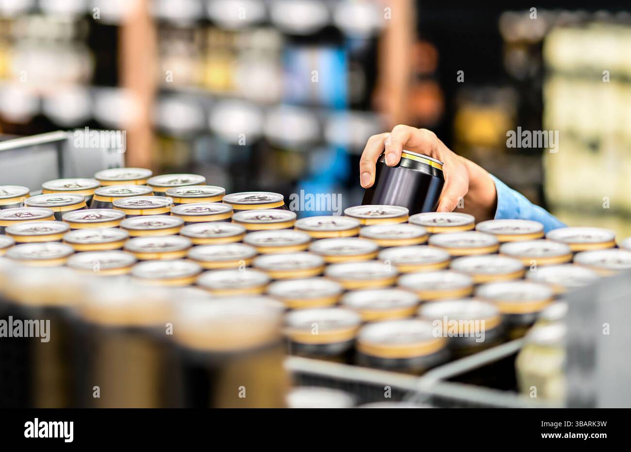 Energy Drink oder Bierdose im Supermarkt. Alkohol Gang im Geschäft. Hand nimmt Cola-Soda-Getränk auf dem Lebensmittelmarkt. Lagerbestand von Einzelhändlern. Stockfoto