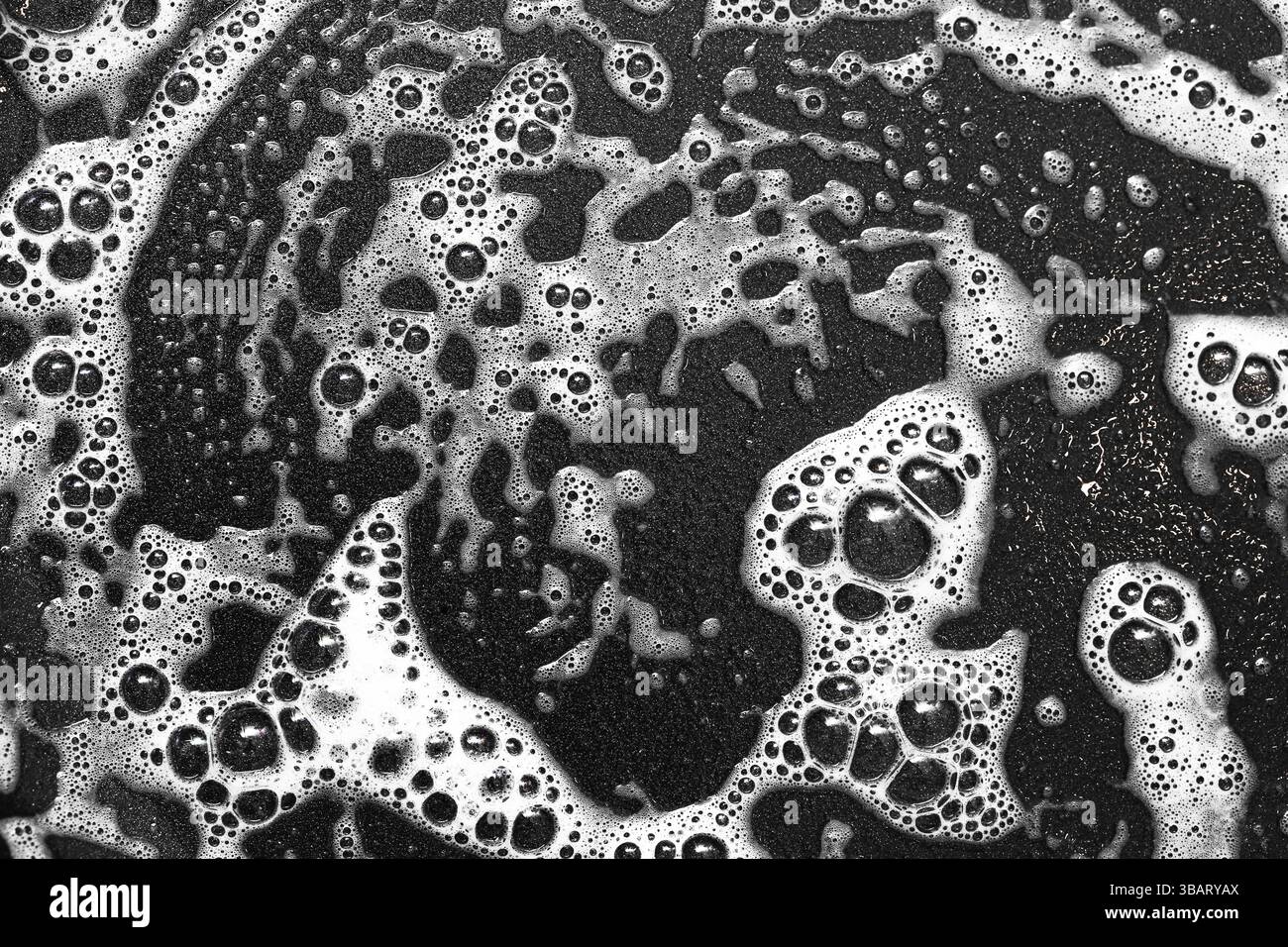 Schaumige Seifenbläschen Textur. Abstraktes Schwarzweiß-Muster. Nahaufnahme von dickem Schaum mit Wasser. Reinigen des Hintergrunds mit kreisförmigen Formen. Stockfoto