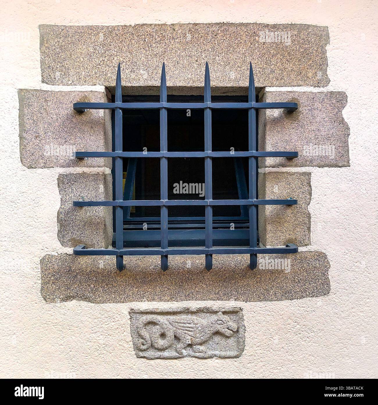 Kleines Fenster mit Granitsteinfassung, robustem Sicherheitsgitter aus Metall und Schnitzereien mit kleinen Tieren - Saint-Léonard-de-Noblat, Haute-Vienne (87), Frankreich. Stockfoto Kleines Fenster mit Granitsteinfassung, robustem Sicherheitsgitter aus Metall und Schnitzereien mit kleinen Tieren - Saint-Léonard-de-Noblat, Haute-Vienne (87), Frankreich. Stockfoto