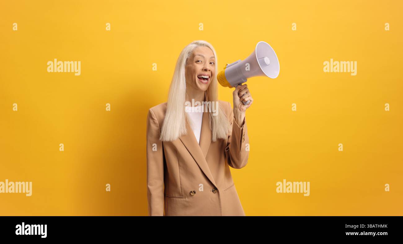 Frau, die mit einem Megaphon auf gelbem Hintergrund spricht Stockfoto