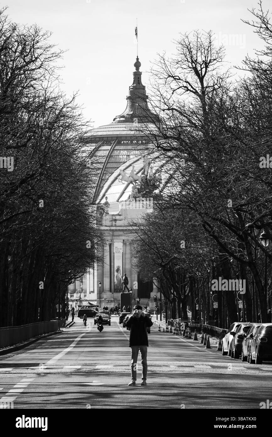 Paris, Frankreich - 23. Februar 2025: Mann mit Kamera vor dem Grand Palais, klassische Pariser Architektur im Hintergrund Stockfoto