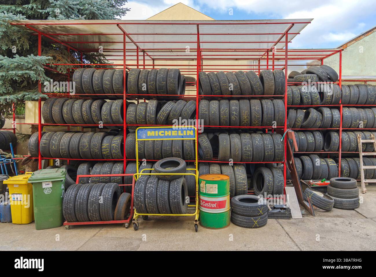Szeged, Ungarn - 31. Juli 2022: Lagerung von Reifen außerhalb der Saison Regalständer Michelin-Schild und Castrol-Ölfassservice-Garage. Stockfoto