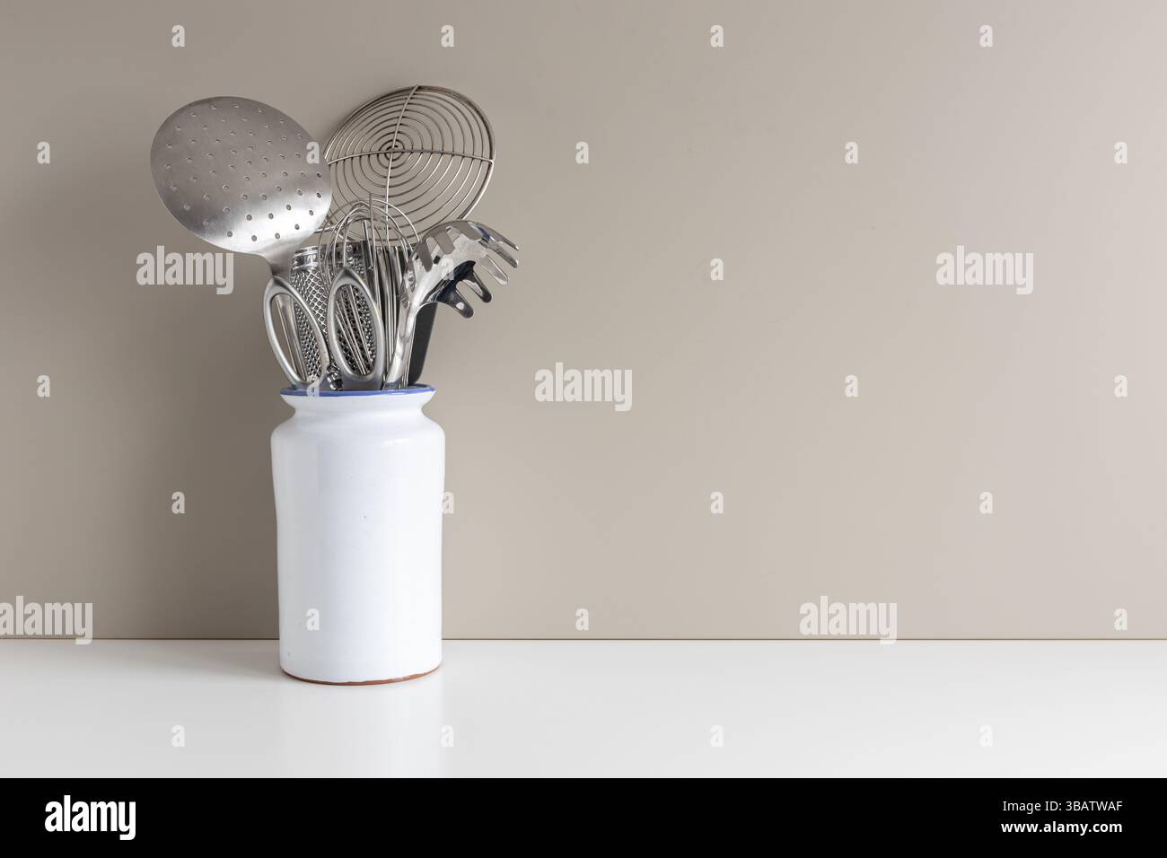 Küchenutensilien in Vase auf dem Tisch mit Kopierraum für Menüs und Rezepte. Minimalistischer Kochhintergrund Stockfoto