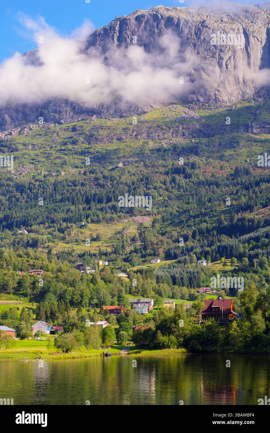 Norwegischer Fjord (Fjord) und Dorfszene mit bergiger Region im Hintergrund. Stockfoto