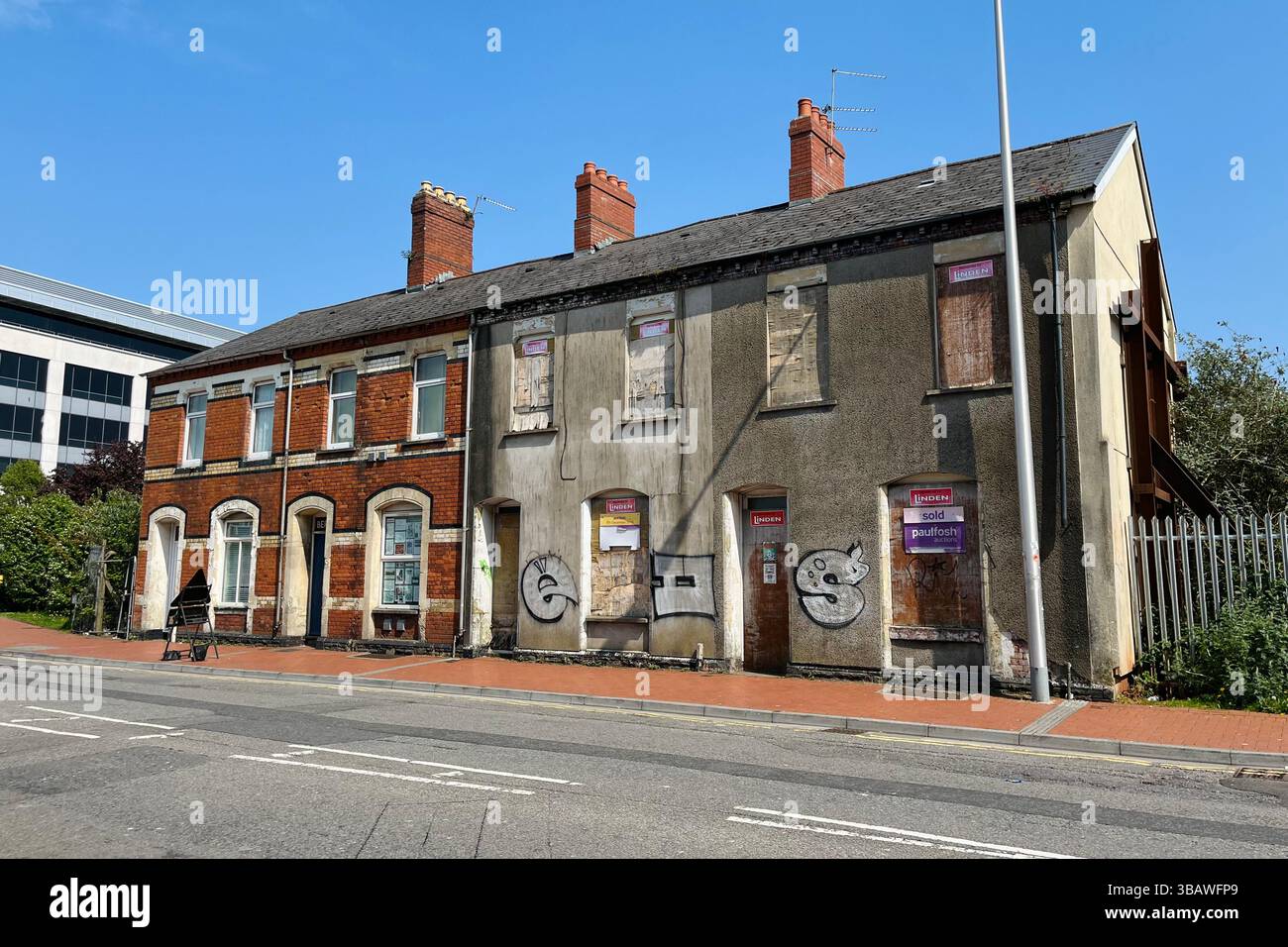 Verfallene Terrassenhäuser mit eingebauten Fenstern und Graffiti in der Nähe von Cardiff Central. Dumballs Road, Cardiff, Wales, Vereinigtes Königreich. April 2025. - Smartphone-aufgenommenes Stockfoto