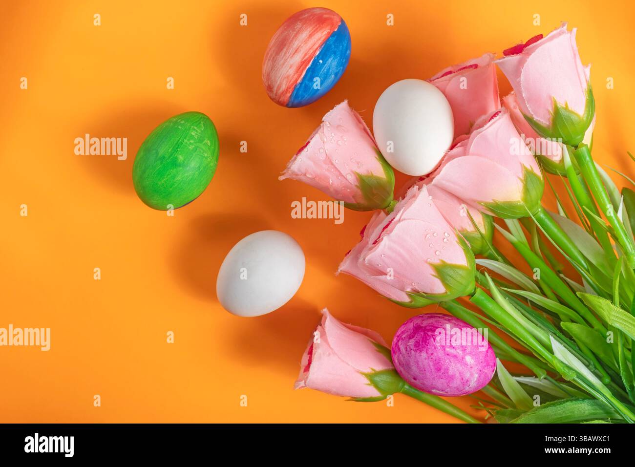 Eine lebendige dekorative Szene mit rosa Tulpen und handbemalten Ostereiern erinnert an die saisonale Feier. Stockfoto