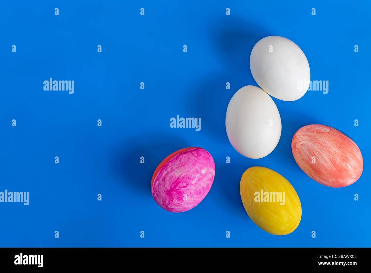 Ein Blick von oben auf die Ostereier, die mit weißen Eiern auf einem hellblauen Hintergrund bemalt sind und den festlichen Geist der Osterfeier vermitteln. Stockfoto