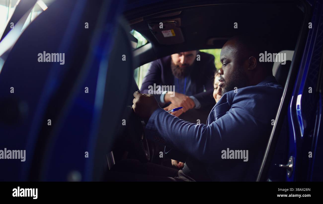 Kunden, die sich im Ausstellungsraum befinden, füllen das Feedback-Formular aus, nachdem sie die Probefahrt beendet haben und sich für den Kauf entschieden haben, zufrieden mit der Hilfe des Verkäufers. Ein Paar kauft ein Auto, nachdem es damit zufrieden war, Kamera B Stockfoto