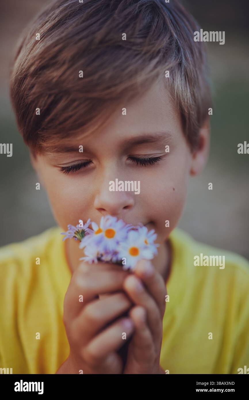 Porträt eines gutaussehenden Jungen, der den Duft von Wildblumen einatmet Stockfoto