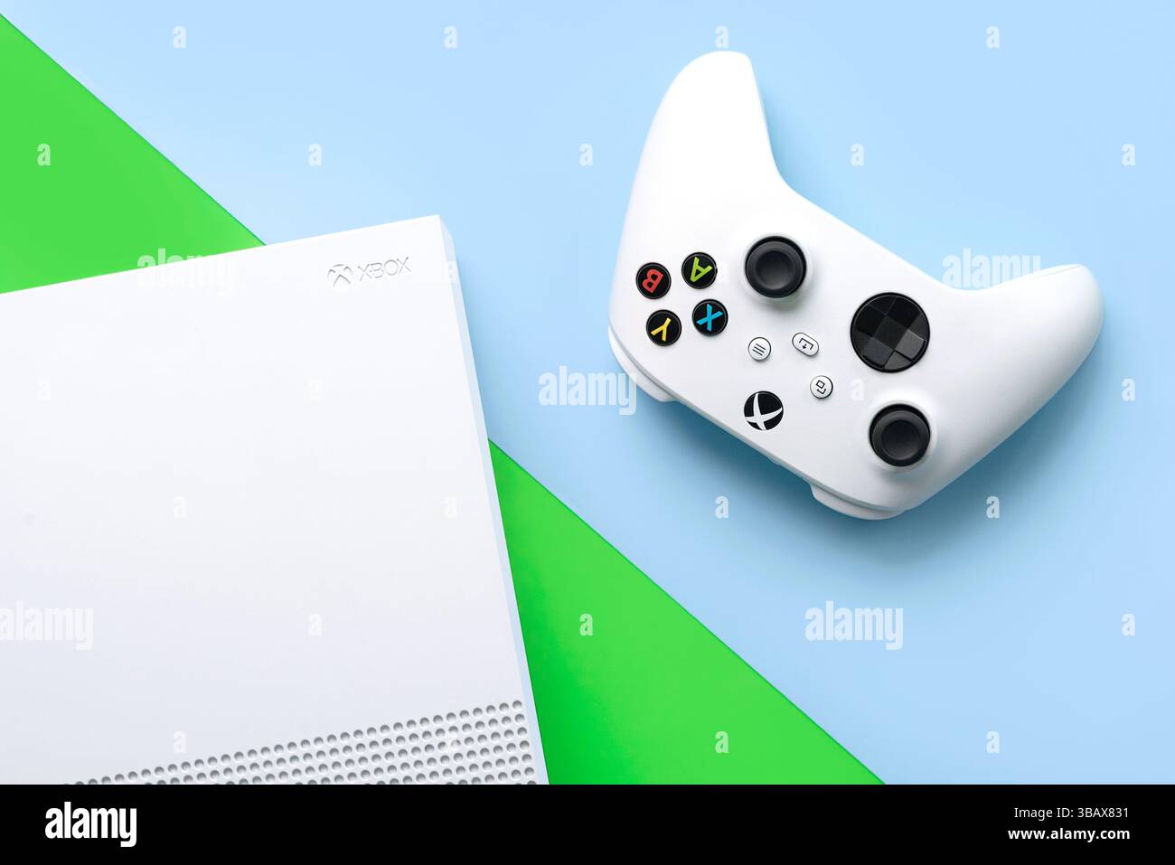 Draufsicht der Xbox One S All Digital Edition-Konsole und des weißen Wireless-Gaming-Controllers über blauem und grünem Hintergrund Stockfoto